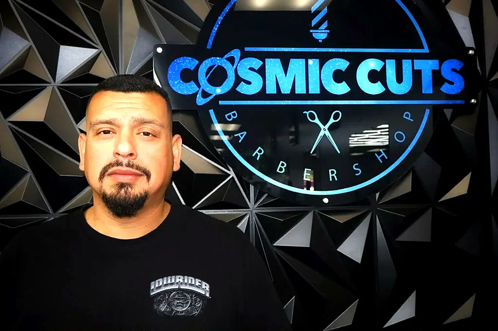 Client after the full service in front of the Cosmic Cuts logo